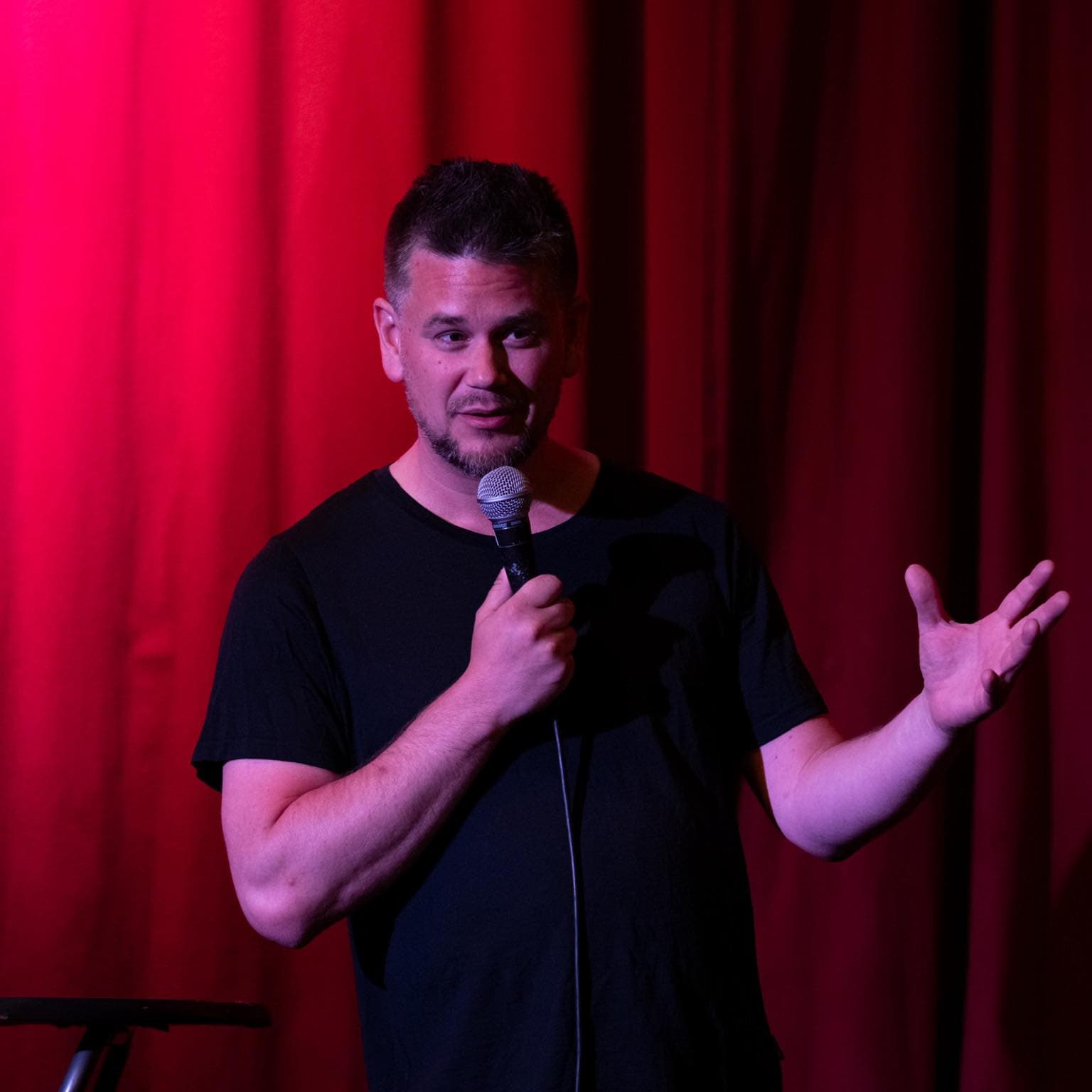 Snorre Bue on stage with a microphone in front of a red curtain
