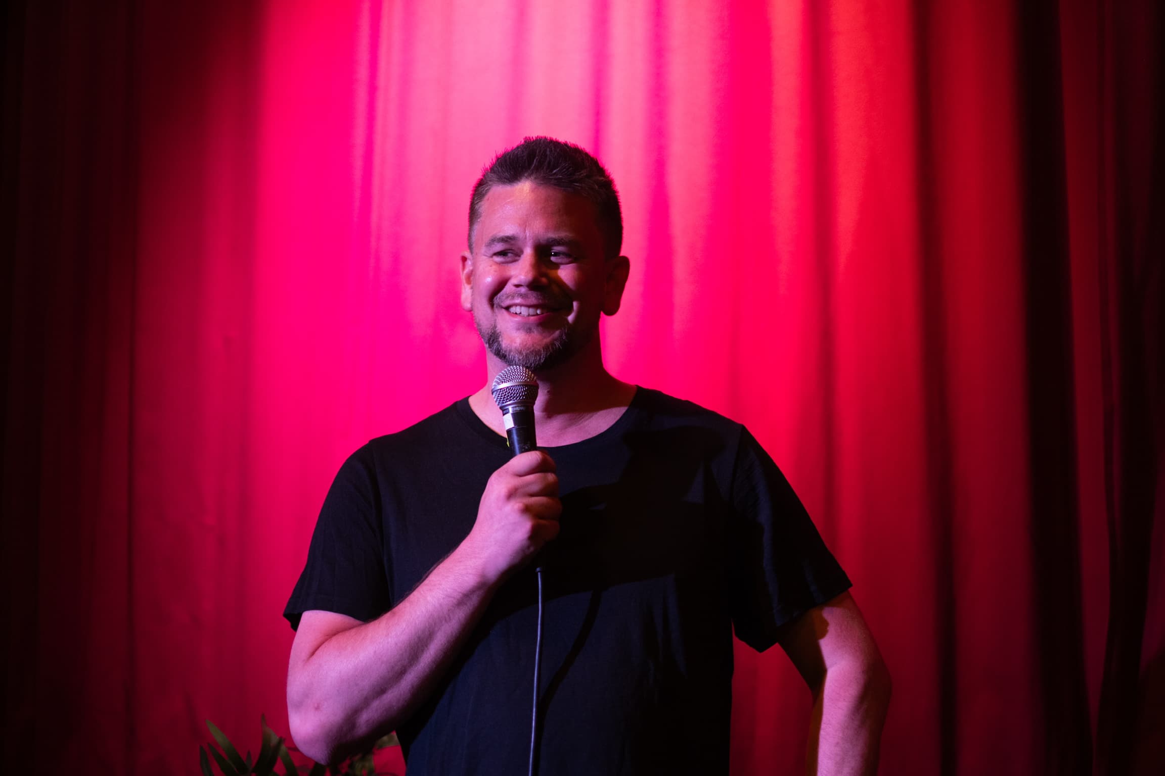 Snorre Bue smiling on stage with a microphone